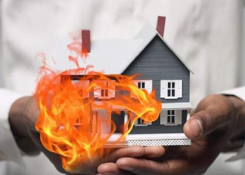 một b&agrave;n tay cầm m&ocirc; h&igrave;nh ng&ocirc;i nh&agrave;, xung quanh c&oacute; ngọn lửa