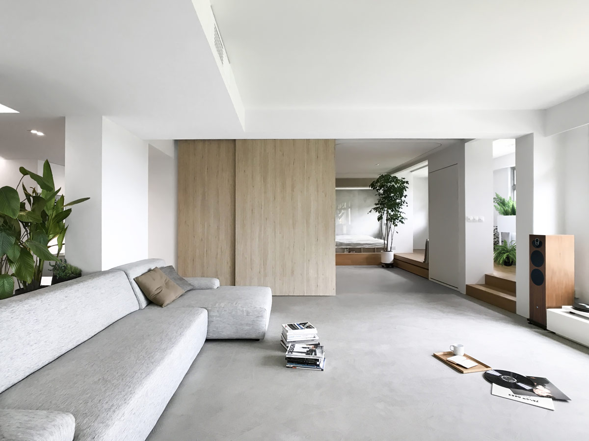 ph&ograve;ng kh&aacute;ch đơn giản với sofa x&aacute;m, c&acirc;y xanh trang tr&iacute;, v&aacute;ch ngăn trượt bằng gỗ