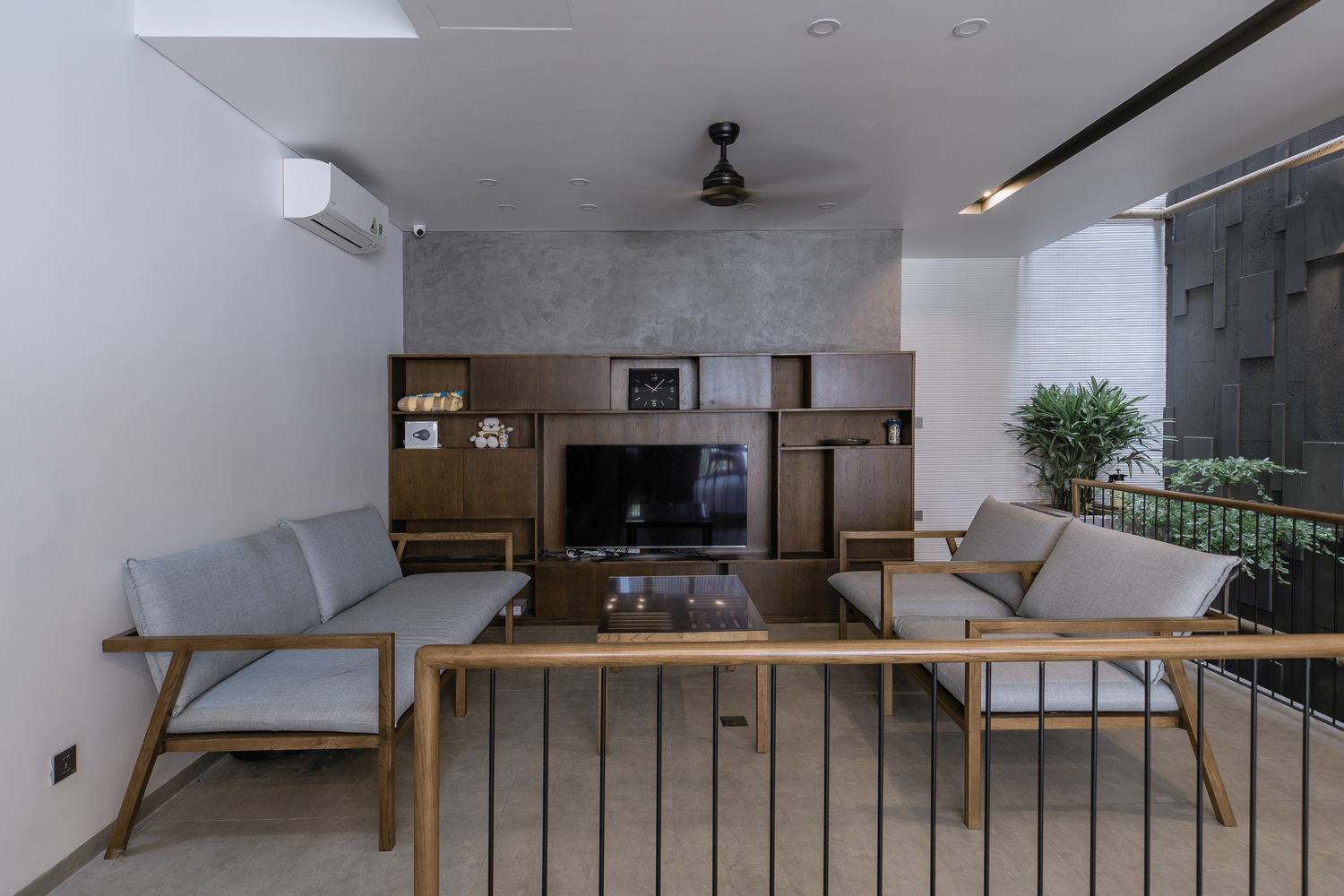 to&agrave;n cảnh ph&ograve;ng kh&aacute;ch với sofa gỗ bọc nệm ghi x&aacute;m, tủ kệ tivi bằng gỗ