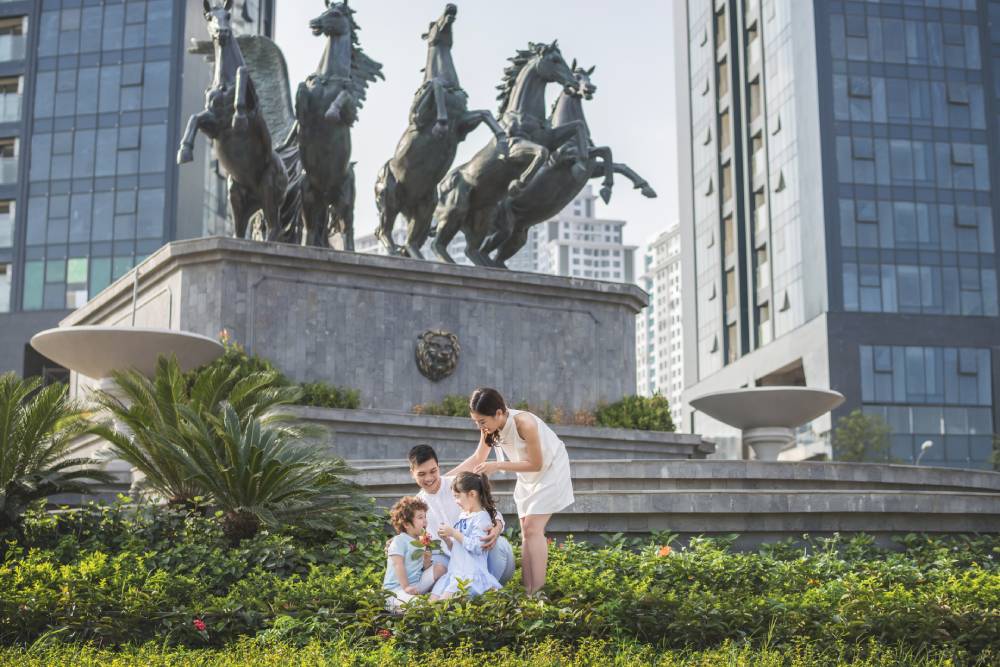 hai vợ chồng và con đang ngồi trước khu đô thị