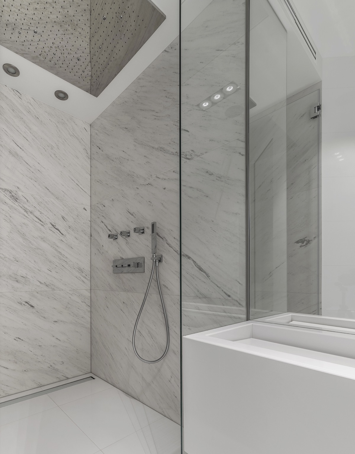 Thiết bị nhà tắm bằng chrome sáng bóng, nổi bật trên nền tường đá cẩm thạch.