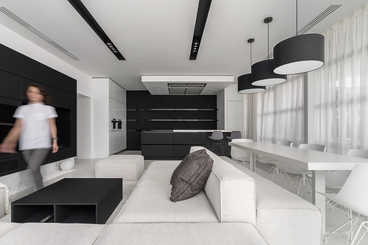 hình ảnh cô gái trẻ đứng trong phòng khách căn hộ 120m2 tông màu đen - trắng chủ đạo