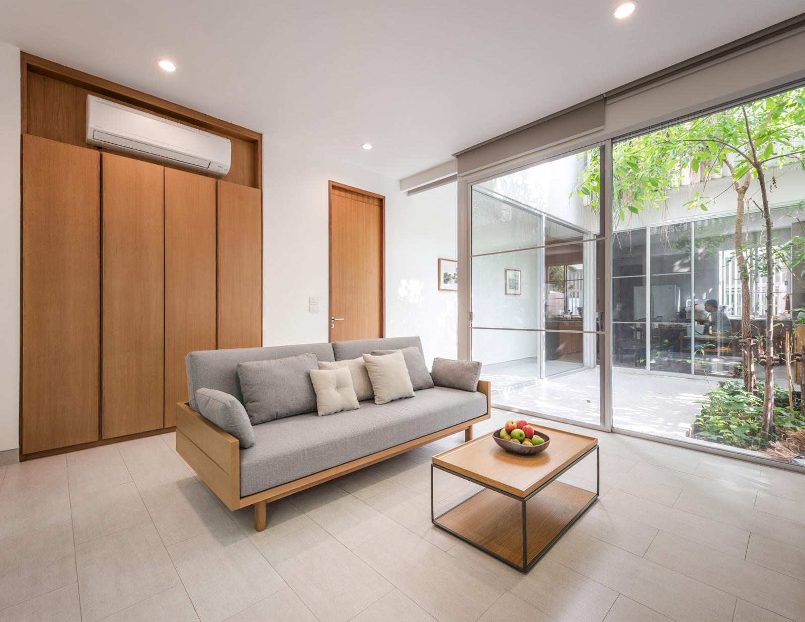 hình anh phòng khách với ghế sofa gỗ, bàn trà, hệ tủ lưu trữ cao kịch trần