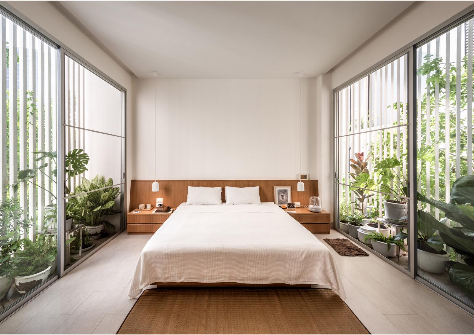 Hai ban công dài và hẹp bao quanh phòng ngủ chính được lấp đầy bởi những chậu cây xanh tốt. Hệ cửa kính trong suốt lấy sáng tự nhiên và thông gió tối ưu cho căn phòng.