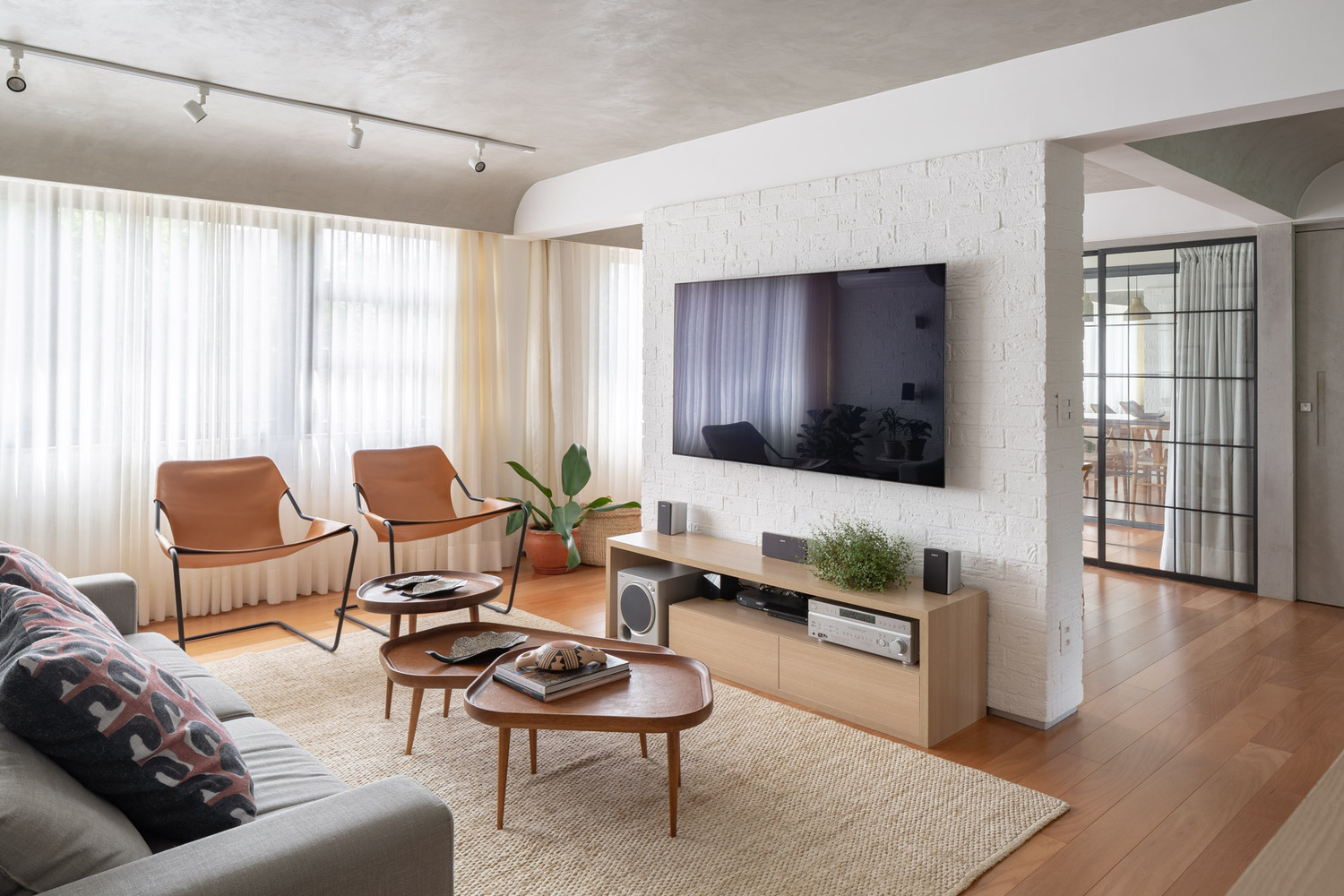 ph&ograve;ng kh&aacute;ch căn hộ 70m2 với sofa x&aacute;m, b&agrave;n tr&agrave; gỗ đ&ocirc;i, r&egrave;m cửa sổ m&agrave;u trắng