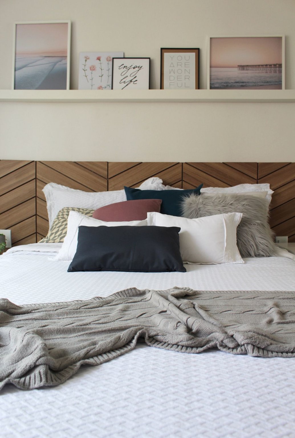 Tường đầu giường được decor tinh tế với kệ mở đặt bộ tranh cảnh biển ho&agrave;ng h&ocirc;n.