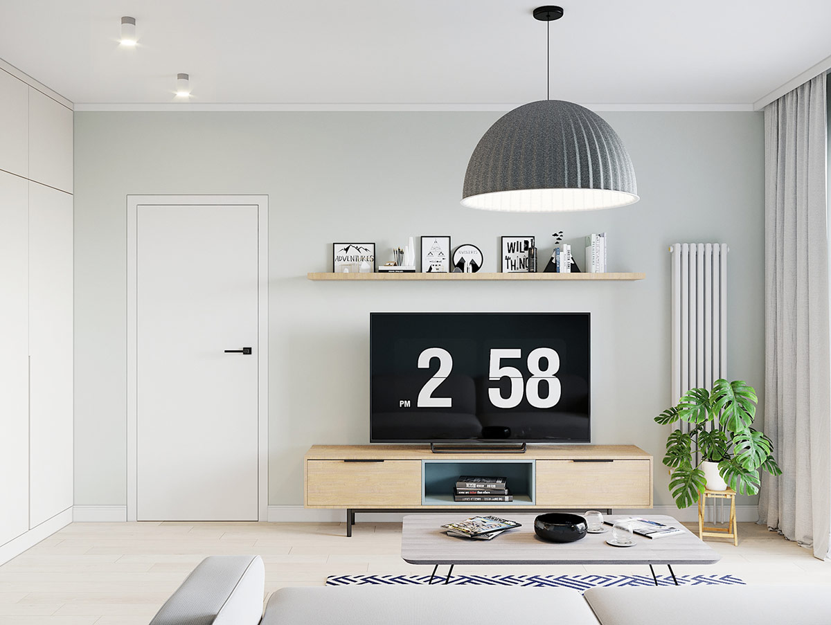 Cạnh tủ kệ tivi là chậu cây xanh mướt, che chắn một phần bộ tản nhiệt, làm dịu sự hiện diện của nó trên tường phòng khách.