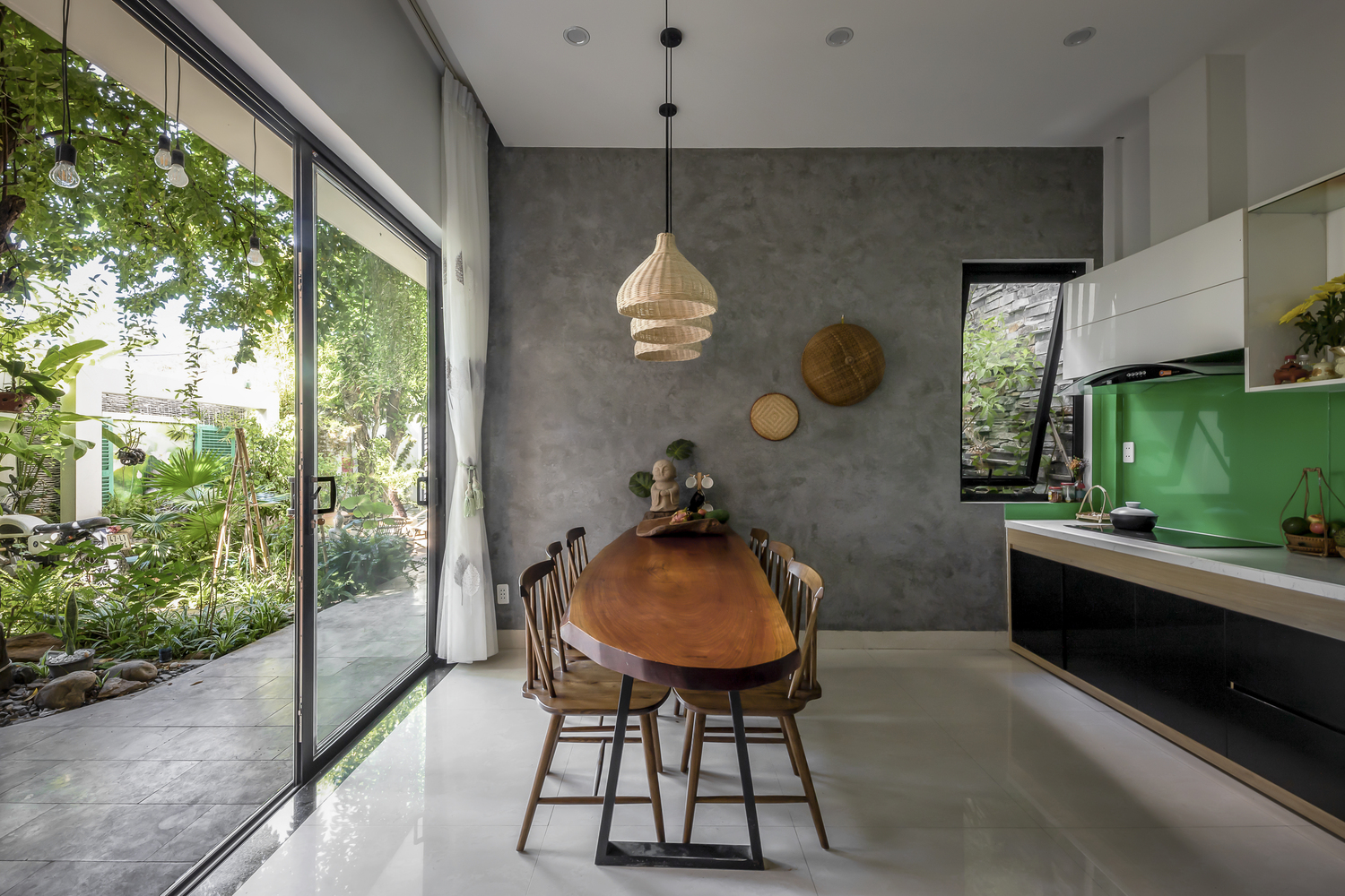 Phòng bếp kết hợp phòng ăn ngập tràn ánh sáng tự nhiên, có cửa trượt kính lớn mở ra khu vườn xanh mát bên cạnh.