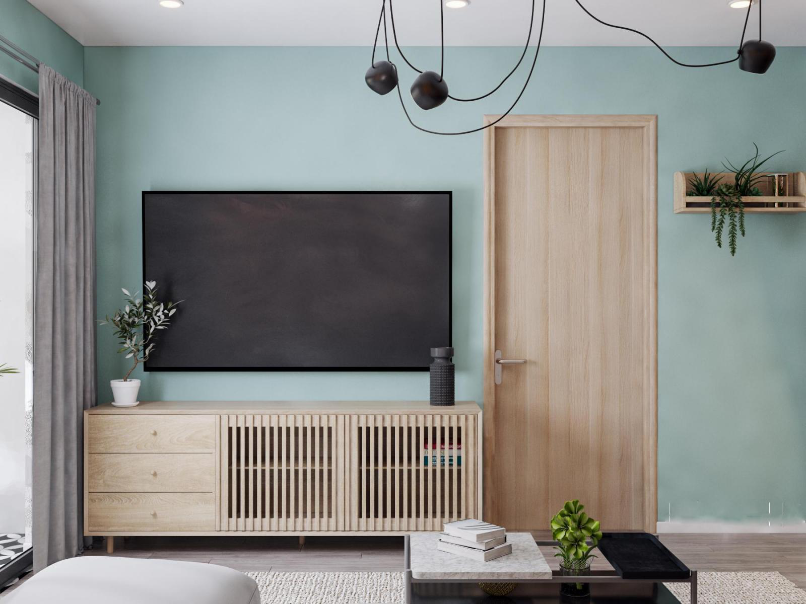 G&oacute;c ph&ograve;ng kh&aacute;ch căn hộ 90m2 với tường m&agrave;u xanh pastel nh&atilde; nhặn, l&agrave;m nền cho nội thất gỗ m&agrave;u s&aacute;ng trở n&ecirc;n nổi bật hơn.