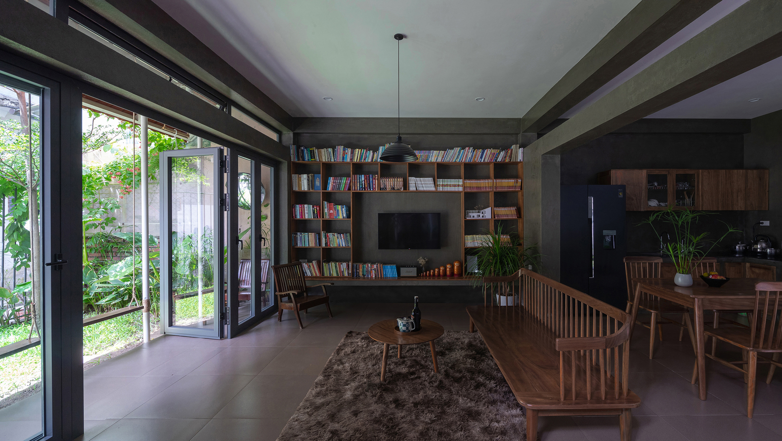 ph&ograve;ng kh&aacute;ch rộng r&atilde;i, tho&aacute;ng s&aacute;ng với gi&aacute; s&aacute;ch cao kịch trần, b&agrave;n ghế bằng gỗ mộc mạc