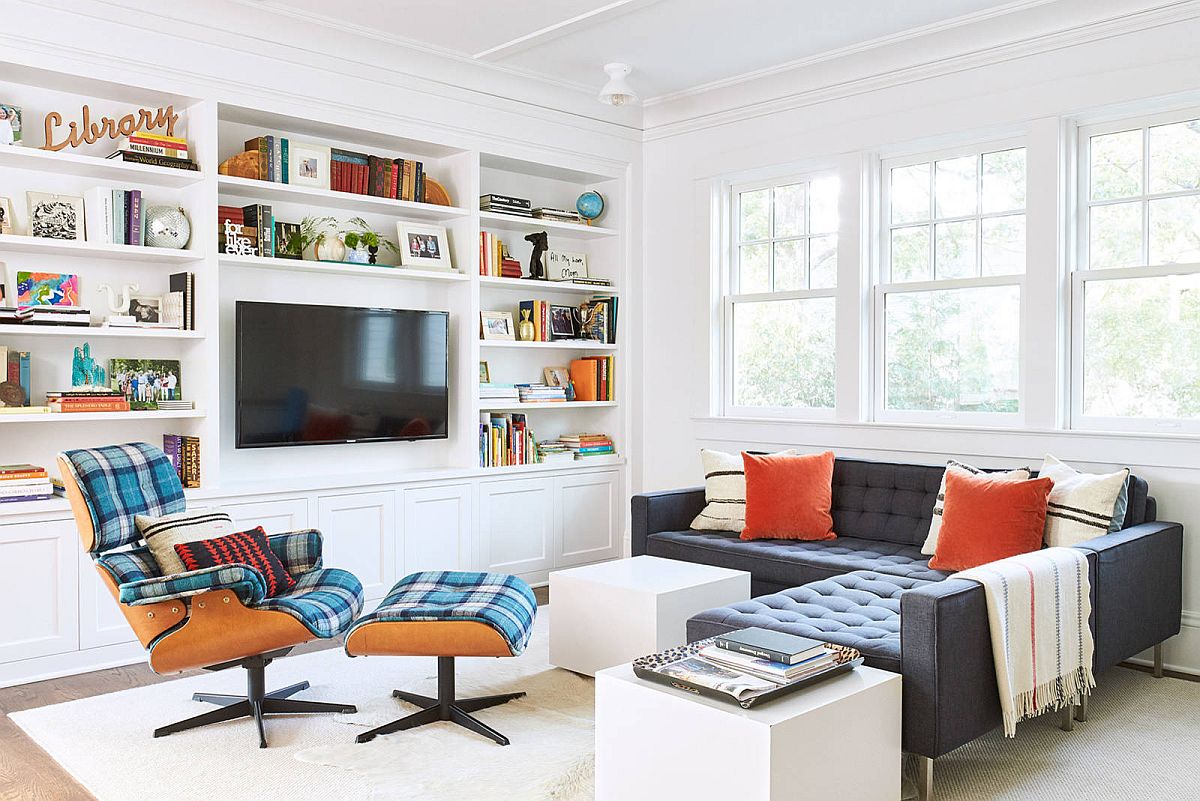 hình ảnh phòng khách thoáng sáng với ghế sofa da màu đen, ghế thư giãn bọc nệm kẻ sọc, giá sách mở màu trắng với tivi ở trung tâm