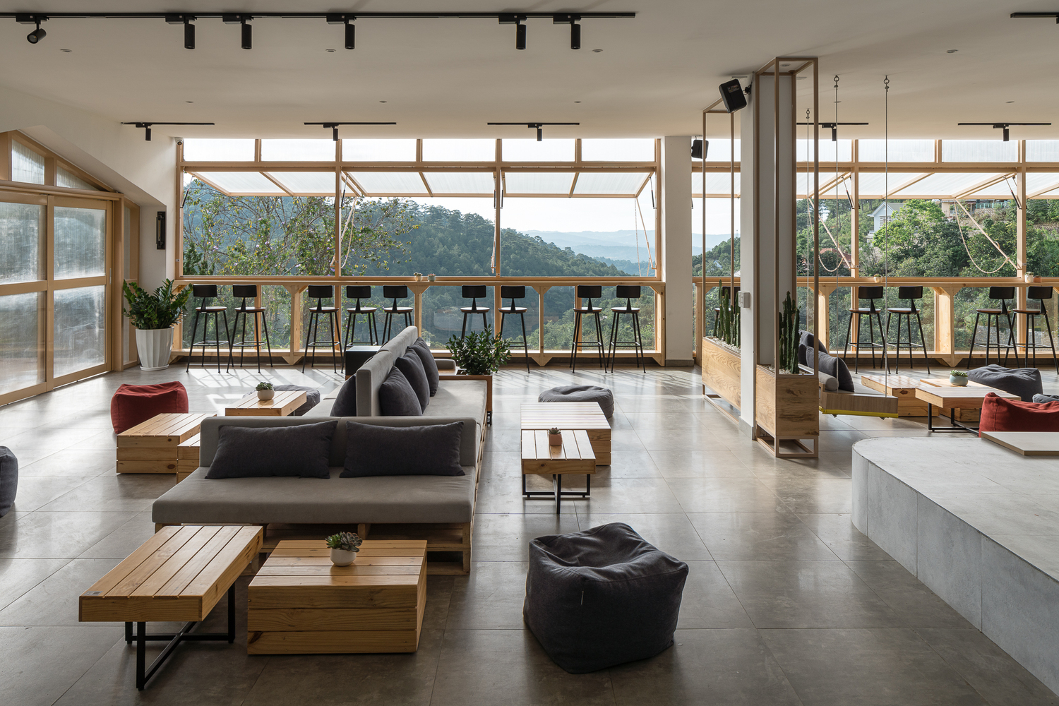 h&igrave;nh ảnh qu&aacute;n c&agrave; ph&ecirc; với b&agrave;n ghế sofa thấp, ghế bar cạnh tường k&iacute;nh trong suốt