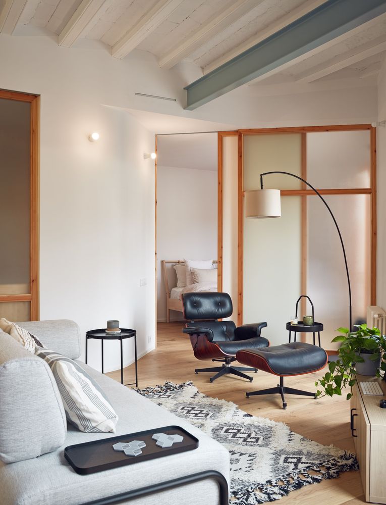h&igrave;nh ảnh ph&ograve;ng kh&aacute;ch với sofa ghi x&aacute;m, b&agrave;n tr&agrave; tr&ograve;n m&agrave;u đen, ghế da thư gi&atilde;n, đen s&agrave;n, thảm trải họa tiết đen - trắng
