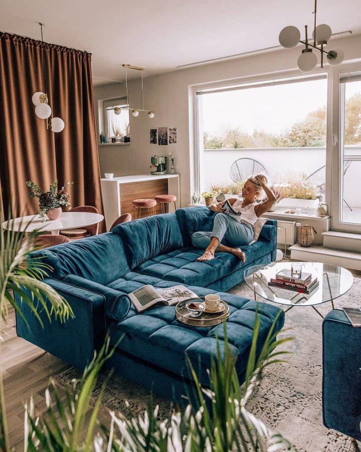 Ghế sofa màu xanh dương trở thành vách ngăn phòng linh hoạt giữa phòng khách với không gian ăn uống và bàn bar ngay cạnh.