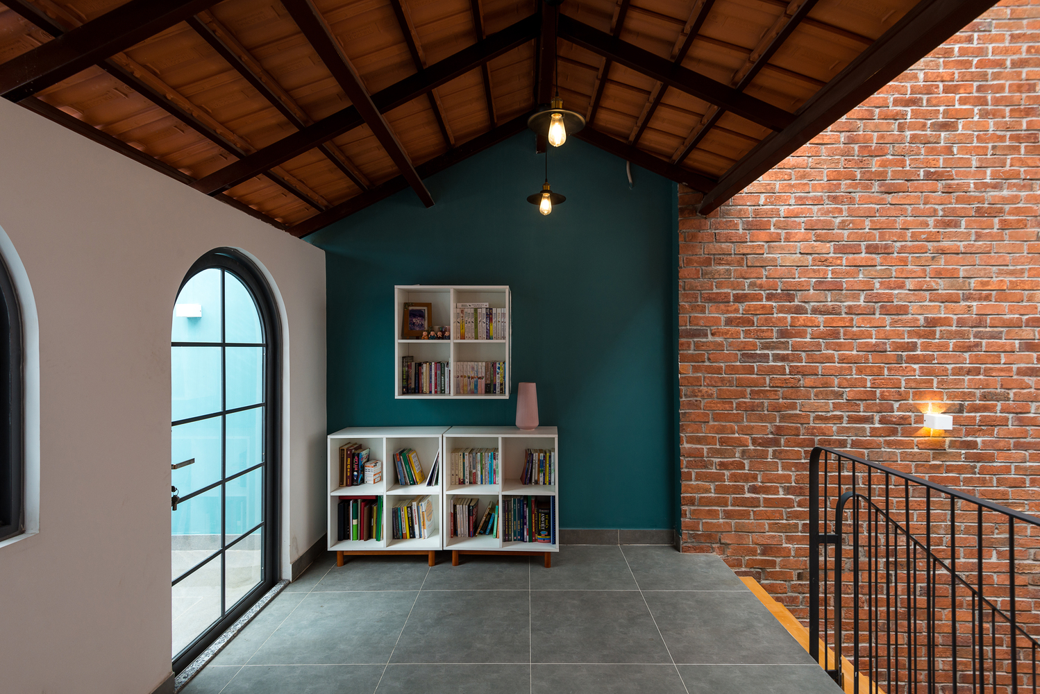g&oacute;c đọc s&aacute;ch ở chiếu nghỉ cầu thang với gi&aacute; s&aacute;ch thấp, khung cửa sổ k&iacute;nh h&igrave;nh v&ograve;m nhẹ nh&agrave;ng