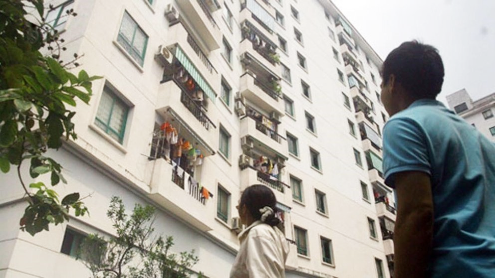 h&igrave;nh ảnh một người đ&agrave;n &ocirc;ng v&agrave; một người phụ nữ đ&atilde; ngước nh&igrave;n l&ecirc;n t&ograve;a nh&agrave; chung cư nh&agrave; ở x&atilde; hội