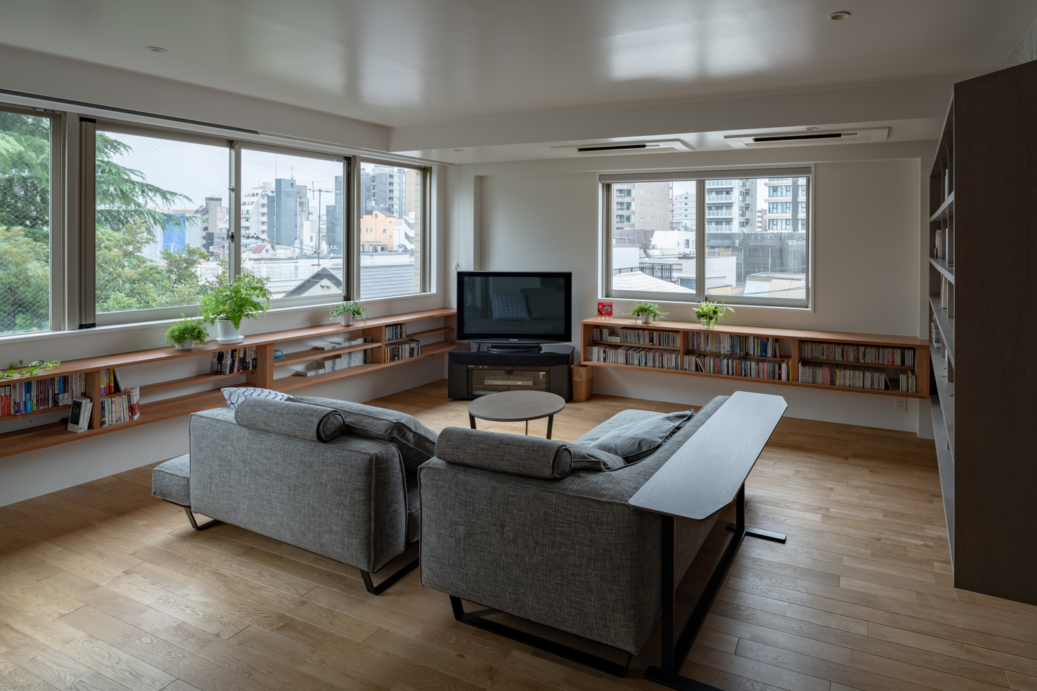 hình ảnh phòng khách căn hộ 98m2 với sofa xám, bàn trà tròn, cửa sổ kính trong suốt