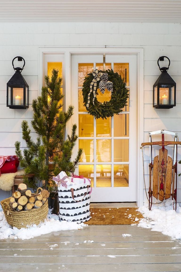 Hình ảnh cận cảnh lối vào với vòng lá xanh treo trên cửa kính, cây thông Noel bên cạnh