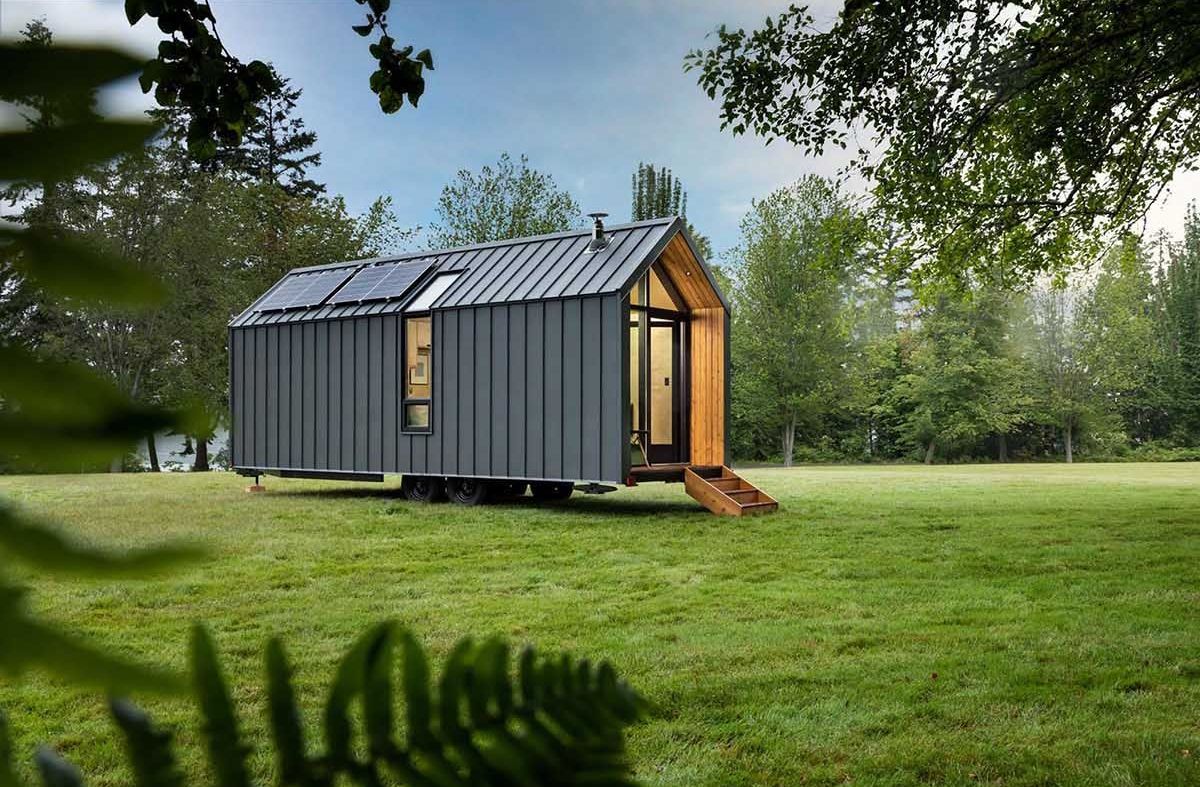 h&igrave;nh ảnh to&agrave;n cảnh ng&ocirc;i nh&agrave; cabin với lớp vỏ kim loại m&agrave;u x&aacute;m đen đặt tr&ecirc;n thảm cỏ xanh mướt