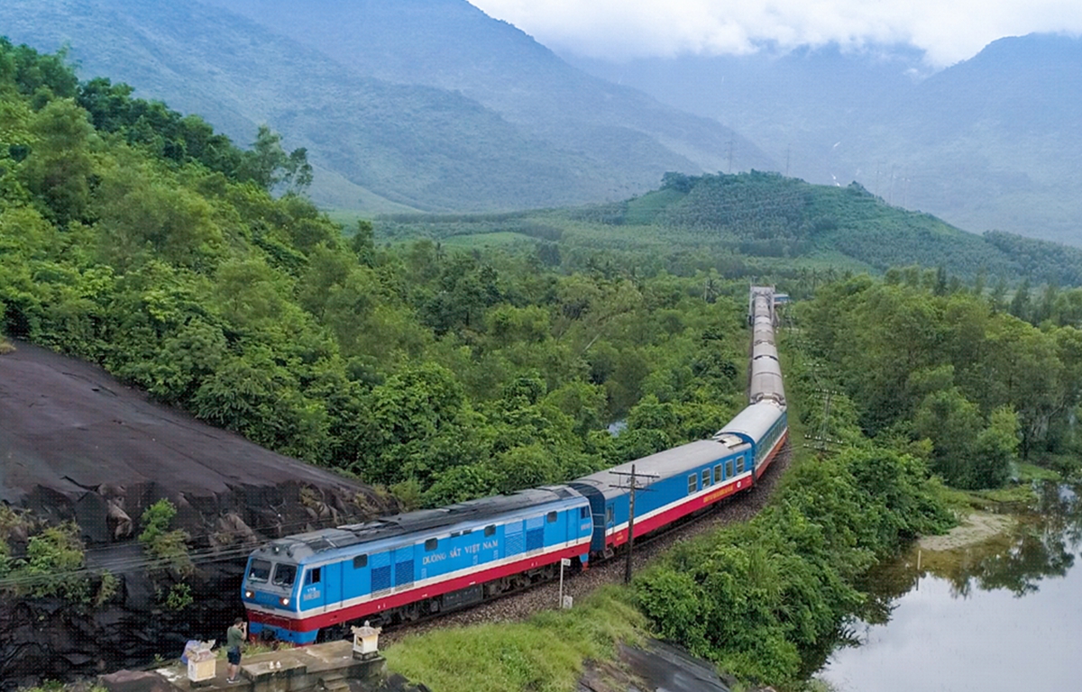 đo&agrave;n t&agrave;u đang chạy qua khu vực đồi n&uacute;i c&oacute; nhiều c&acirc;y xanh