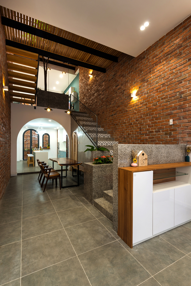 hình ảnh tường gạch mộc ở cầu thang nhà phố, cạnh đó là bàn ăn