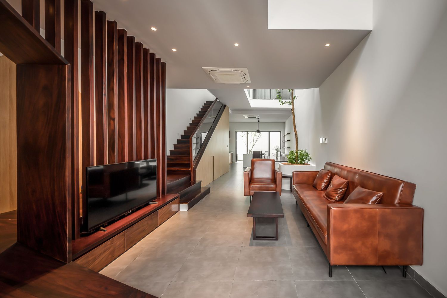 hình ảnh phòng khách nhà phố nổi bật với sofa da bò, lam gỗ lớn phía sau tivi