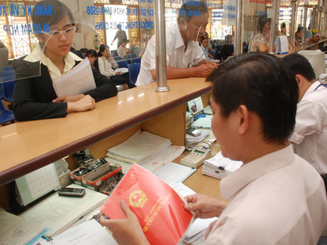 h&igrave;nh ảnh b&ecirc;n trong một văn ph&ograve;ng quản l&yacute; đất đai, hai người đang giao dịch li&ecirc;n quan tới sổ đỏ