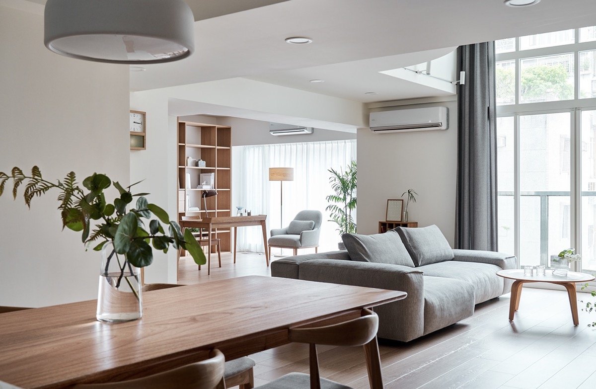hình ảnh cận cảnh bàn ăn bằng gỗ, phía trên có đặt bình hoa trang trí, nhìn ra khu phòng khách và phòng làm việc thoáng sáng