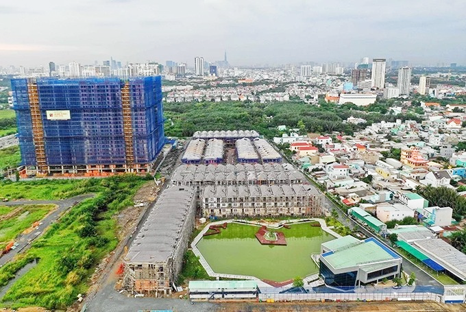 h&igrave;nh ảnh một dự &aacute;n nh&agrave; ở vi phạm x&acirc;y dựng tại TP.HCM với khu nh&agrave; ở liền kề thấp tầng, t&ograve;a chung cư cao tầng x&acirc;y dựng dở dang, v&acirc;y lưới m&agrave;u xanh dương