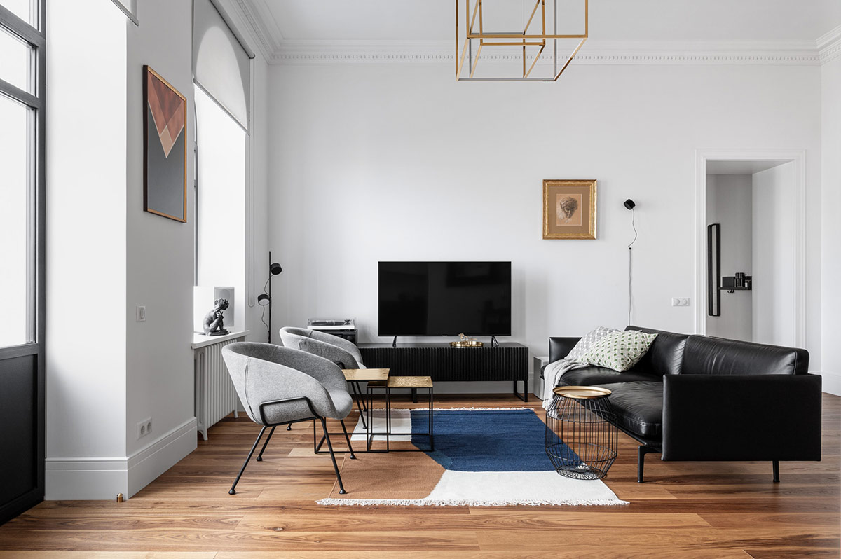 Trong ph&ograve;ng kh&aacute;ch căn hộ tối giản, ghế sofa da m&agrave;u đen ch&acirc;n cao tạo điểm nhấn h&uacute;t mắt, nổi bật tr&ecirc;n ph&ocirc;ng nền m&agrave;u trắng chủ đạo.