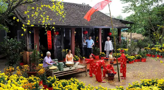 hình ảnh gia đình quây quần trước sân nhà đón Tết, mai vàng, cụ già, em nhỏ mặc áo dài đỏ...