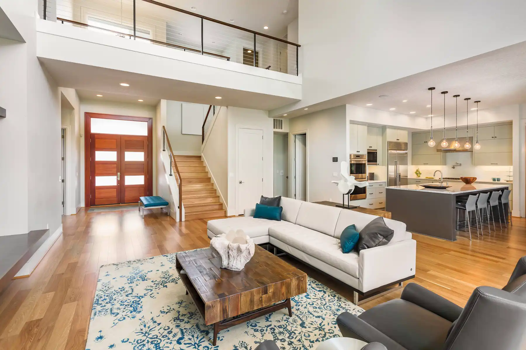 hình ảnh phòng khách rộng rãi với sofa màu trắng, gối tựa màu xanh dương, bàn trà gỗ, sàn gỗ