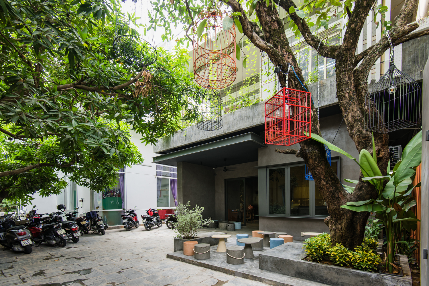 cận cảnh mặt ngoài quán cà phê the 59 ở Đà Nẵng với cây xanh, bàn ghế sắt màu sắc, lồng chim