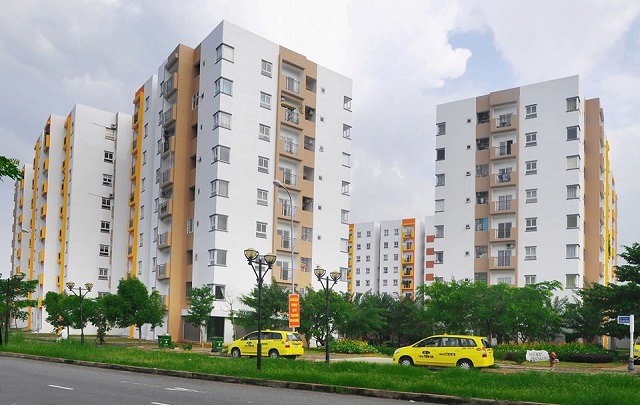 hình ảnh các tòa nhà ở xã hội đã hoàn thiện với mặt ngoài màu trắng, nâu, sọc vàng, 2 ô tô màu vàng
