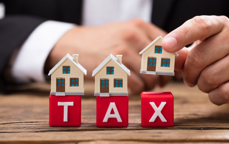 hình ảnh bàn tay người đàn ông mặc vest đen xếp mô hình ngôi nhà lên dòng chữ TAX