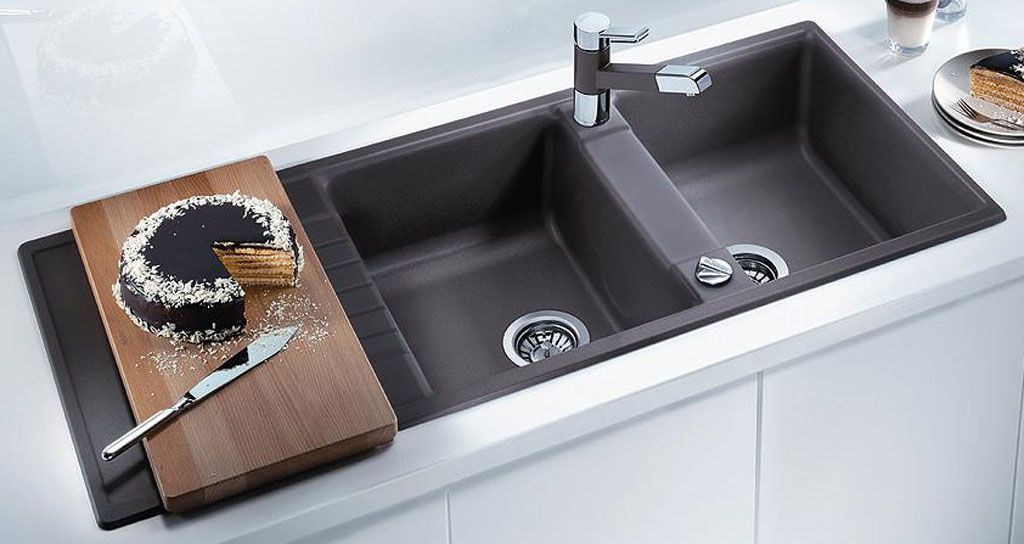 hình ảnh cận cảnh bồn rửa chén đôi mfu đen, bên cạnh là thớt gỗ đựng bánh gato cắt dở