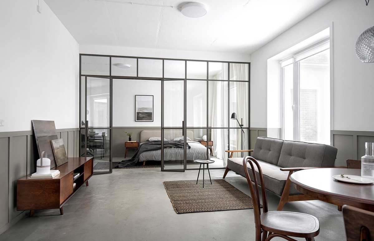 h&igrave;nh ảnh ph&ograve;ng kh&aacute;ch căn hộ 58m2 với s&agrave;n b&ecirc; t&ocirc;ng m&agrave;i, tủ tivi bằng gỗ, ghế sofa m&agrave;u x&aacute;m, cạnh đ&oacute; l&agrave; b&agrave;n ăn tr&ograve;n, cửa k&iacute;nh trong suốt dẫn v&agrave;o ph&ograve;ng ngủ b&ecirc;n trong
