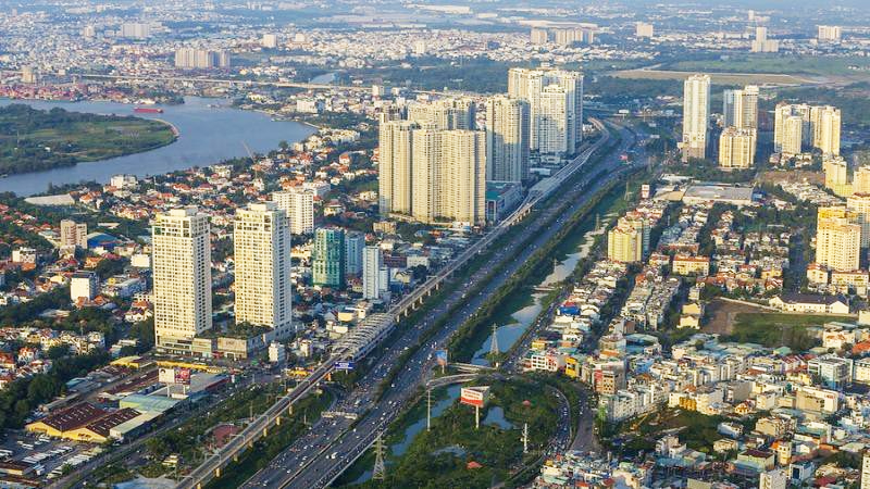 hình ảnh một góc TP.HCM nhìn từ trên cao với nhiều tòa nhà cao tầng xen kẽ khu dân cư thấp tầng, cây xanh, sông nước