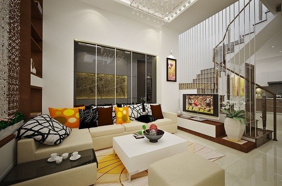 Kh&ocirc;ng gian ph&ograve;ng kh&aacute;ch sang trọng, hiện đại với bộ ghế sofa m&agrave;u trắng ng&agrave; thanh lịch, l&agrave;m nền cho những chiếc gối tựa m&agrave;u sắc trở n&ecirc;n nổi bật hơn. Ph&ograve;ng kh&aacute;ch ph&acirc;n t&aacute;ch với cầu thang bởi v&aacute;ch ngăn mở th&ocirc;ng tho&aacute;ng.