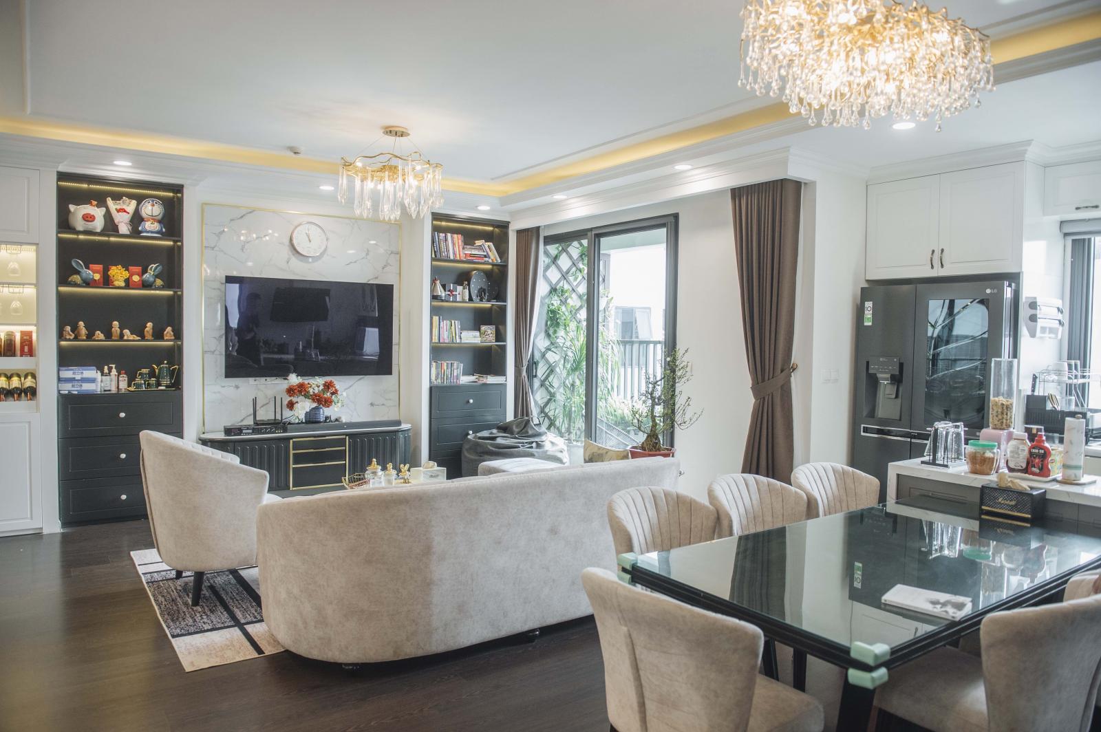 Bếp và phòng khách liên thông với nhau nhằm tăng cường sự tương tác, gắn kết giữa các thành viên gia đình. Nơi đây được bố trí hai chiếc đèn chùm kiểu dáng tinh tế.
