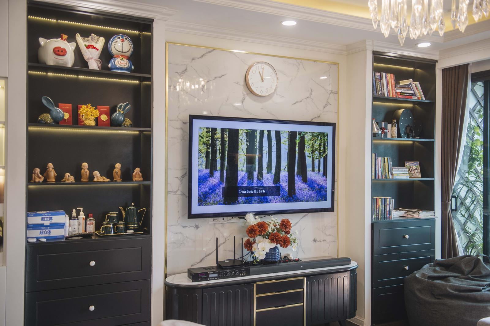 Hệ tủ kệ trang trí và giá sách tông màu đen sang trọng được thiết kế đối xứng qua kệ tivi cùng tông màu tạo thành một thể thống nhất, hoàn chỉnh.
