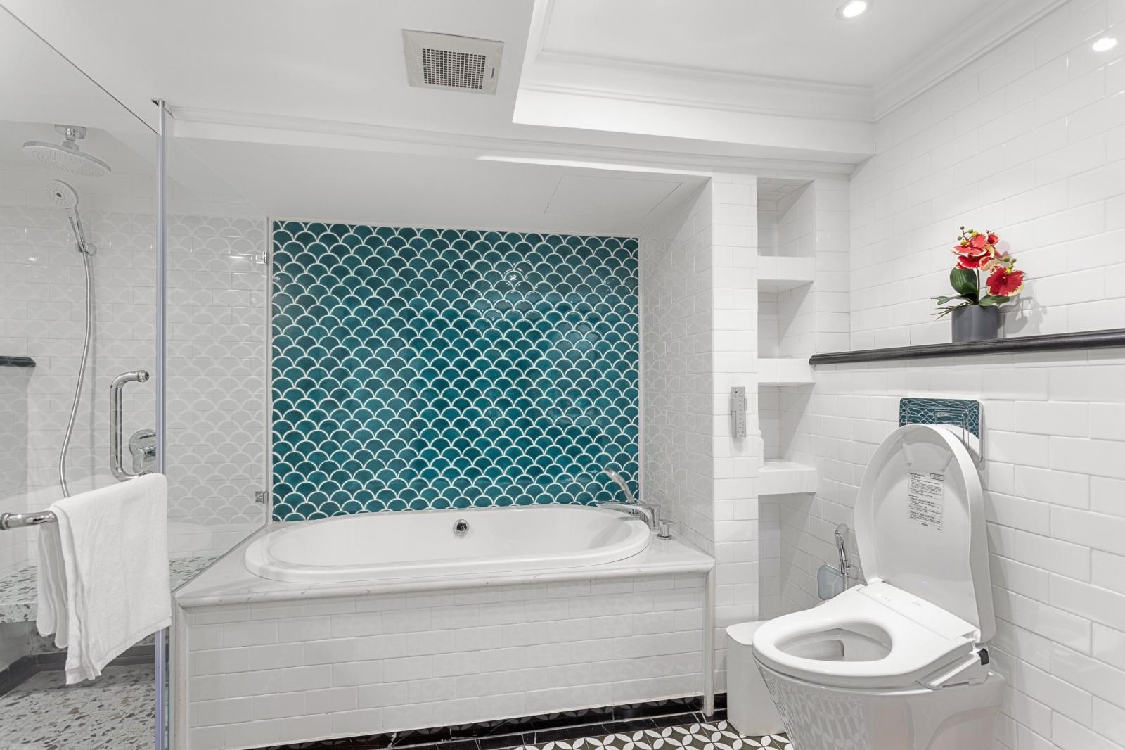 Gạch ốp tường họa tiết vảy cá màu xanh ngọc tạo điểm nhấn cho khu vực bồn tắm.