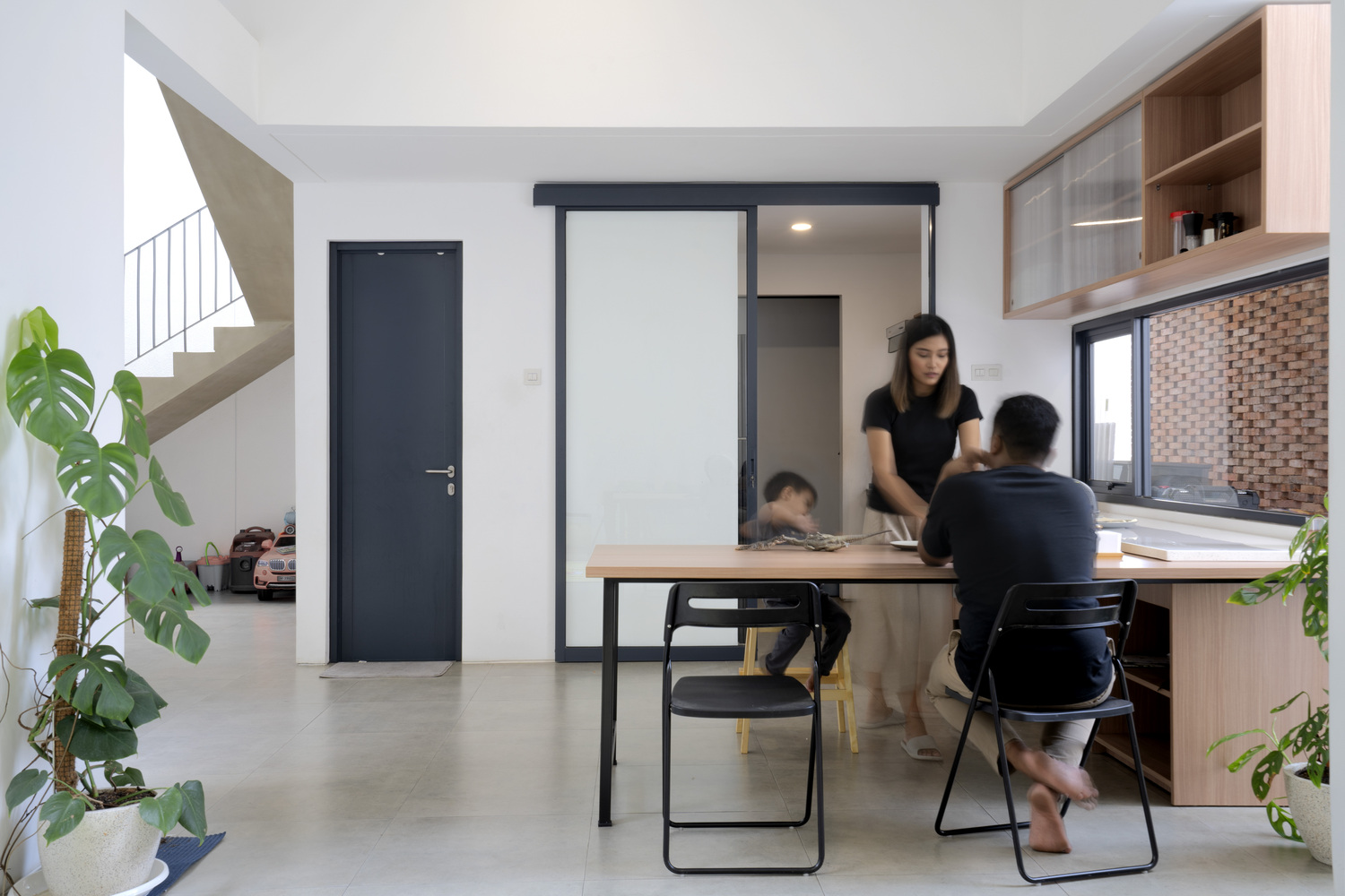 Sàn bê tông mài màu xám hài hòa với tường màu trắng và khung cửa, cửa màu đen giúp cân bằng bảng màu một cách tinh tế.