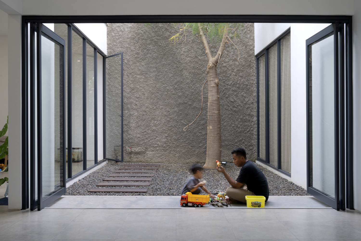 hình ảnh 2 bố con ngồi chơi ở khoảng trống sân trong ngôi nhà