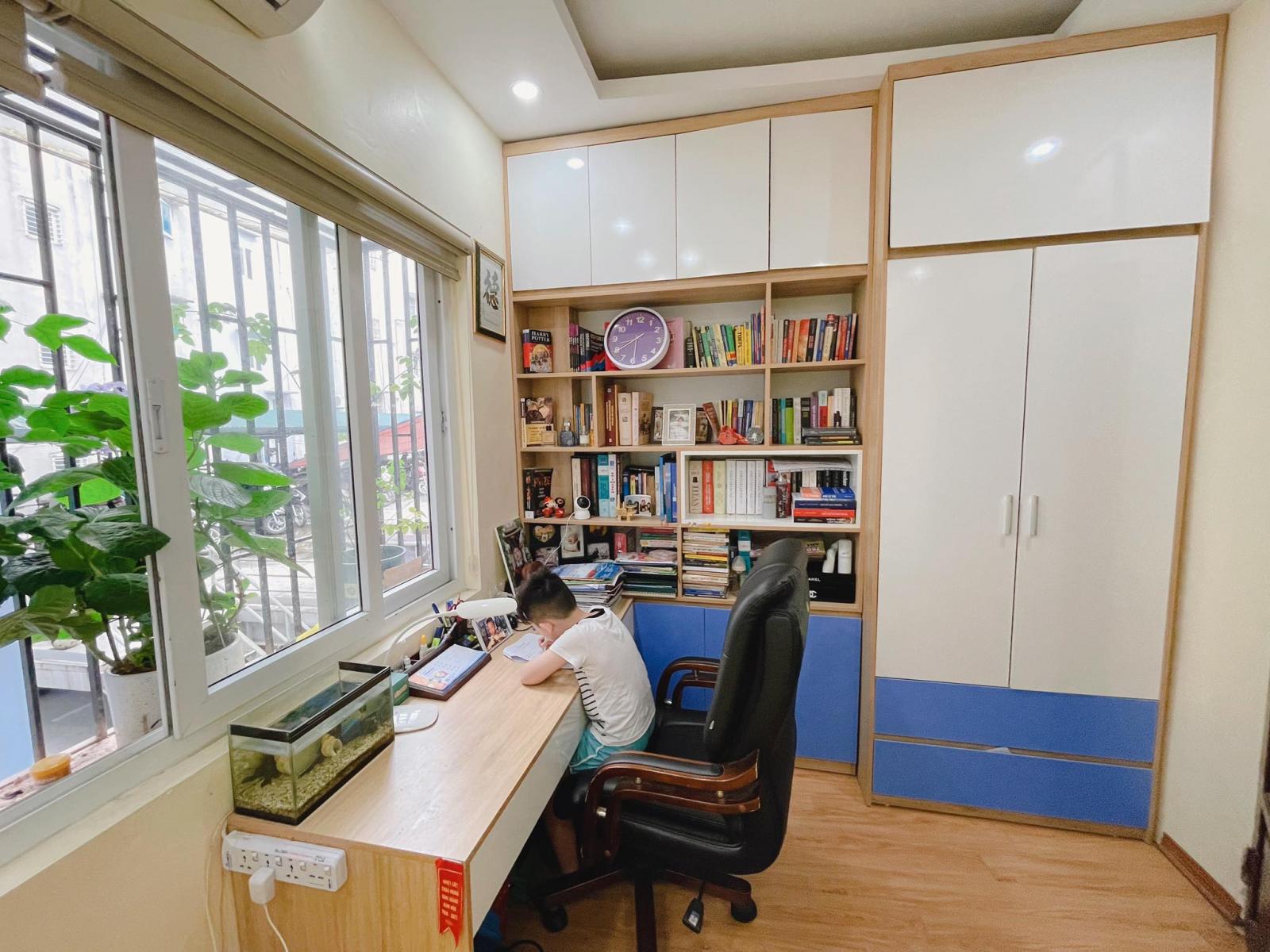 b&eacute; trai đang ngồi ở b&agrave;n cạnh cửa sổ