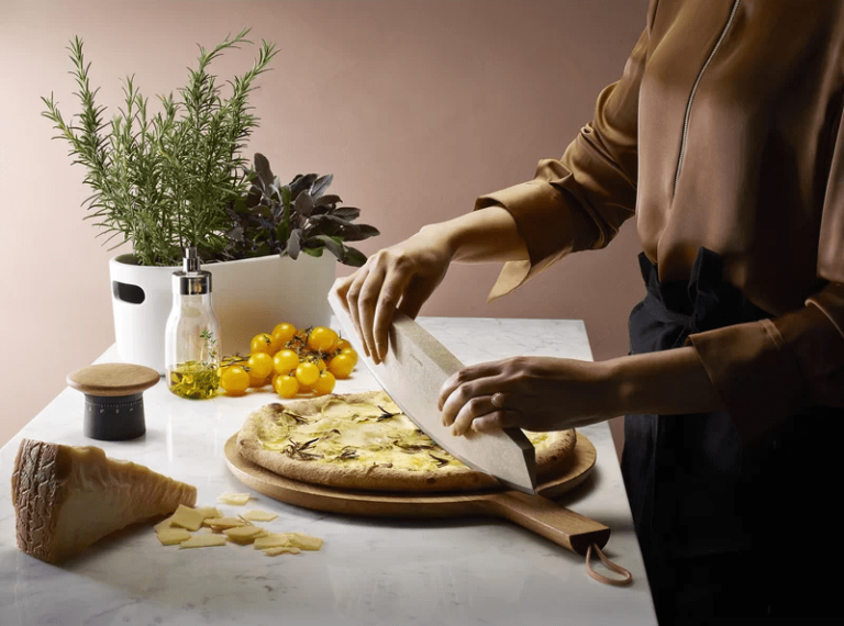 h&igrave;nh ảnh cận cảnh người cắt pizza tr&ecirc;n thớt gỗ