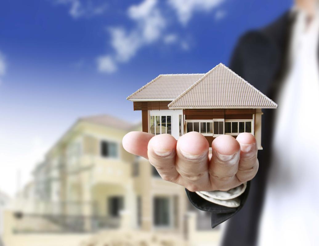 hình ảnh cận cảnh bàn tay nâng đỡ mô hình ngôi nhà minh họa cho nhà xây theo tiến độ