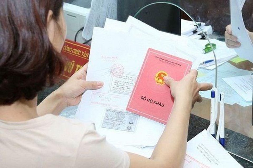 h&igrave;nh ảnh một người phụ nữ ngồi sau cửa k&iacute;nh cầm cuốn sổ hộ khẩu tr&ecirc;n tay minh họa cho Luật Cư tr&uacute; 2020