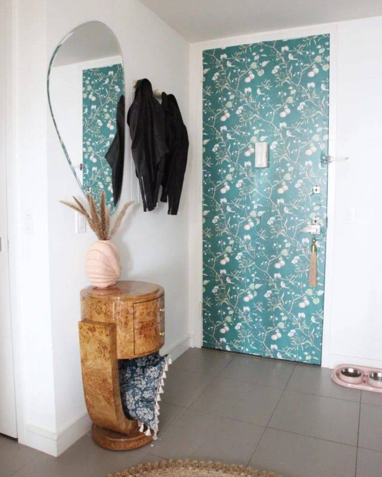 lối v&agrave;o nh&agrave; với gương bất đối xứng, m&oacute;c treo &aacute;o kho&aacute;c, tủ gỗ bo tr&ograve;n, giấy d&aacute;n tường m&agrave;u xanh họa tiết hoa l&aacute;