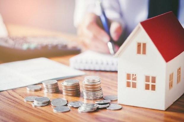 hình ảnh cận cảnh các cọc tiền xu đặt cạnh mô hình ngôi nhà mái đỏ